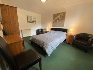 a bedroom with a bed and a chair and a desk at The Kennels Ellary in Lochgilphead