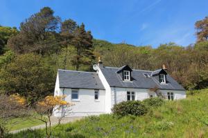 a white house with a black roof on a hill at The Kennels Ellary in Lochgilphead