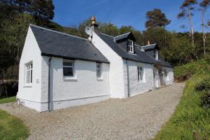 a white house with a black roof on a gravel road at The Kennels Ellary in Lochgilphead +5 photos