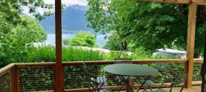 a balcony with a table and chairs and a view of the water at Camping Onlycamp Au Cœur du Lac - Lac d'Annecy in Sévrier +8 photos