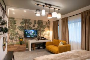 a bedroom with a bed and a yellow chair and a television at RUELLE Chateau Boutique- adults only in Sinaia