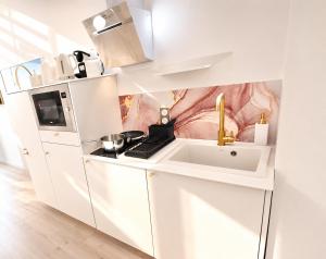 a white kitchen with a sink and a microwave at MRODBNB - Escapade Romantique - Appart Neuf- 25m Plage & Resto - Ciné - Popcorn - Ciel de Pluie XXL in Cancale
