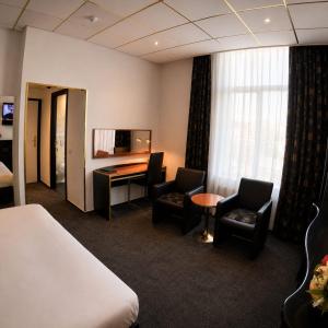 a hotel room with a bed and a desk and chairs at Hotel Le Beau Rivage in Middelburg