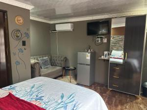 a bedroom with a bed and a couch and a kitchen at Lake boutique hotel empire in Thohoyandou