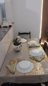 a table with plates and utensils on it at Cantinho da Alzira - Sobrado in Iguaba Grande