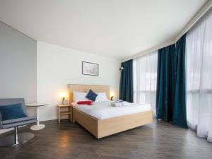 a bedroom with a bed and a desk and a chair at Novotel Senart Golf De Greenparc in Saint-Pierre-du-Perray