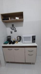 a small kitchen with a microwave and a stove at Cantinho da Alzira - Sobrado in Iguaba Grande