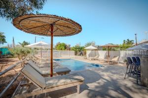 a pool with an umbrella and lounge chairs and a swimming pool at THE SPOT GLAMPING STUDIOS PROTARAs in Paralimni