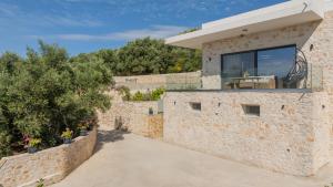 a house with a large window on the side of a stone wall at Villa Mimoza Apelati in Keri