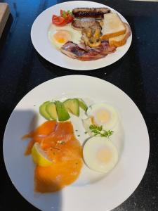 two plates of food with eggs and bread on a table at Spring Garden Cottage in Wadebridge +10 photos