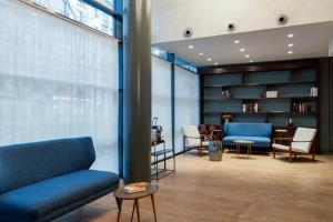a waiting room with blue furniture and a book shelf at Hôtel Sanso by HappyCulture in Paris