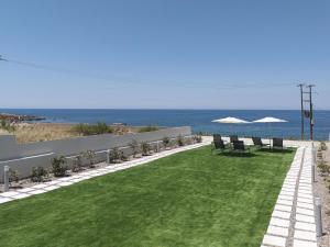 a lawn with chairs and umbrellas next to the ocean at MGM Suites in Panormos Rethymno +77 photos