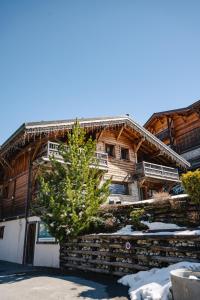 a log cabin in the snow with a tree in front at Appartement Corniche - MultiPass in Les Gets