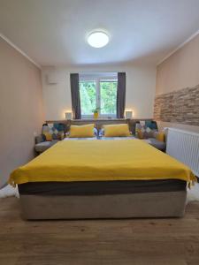 a bedroom with a large yellow bed and a couch at Apartment Jurček with jacuzzi & sauna in Luče