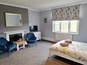 a bedroom with a bed and two chairs and a fireplace at Care Ashore Guest Rooms in Cranleigh