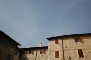 a stone building with red windows and a blue sky at Residenza I Due Mondi in Spoleto