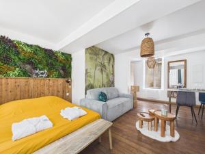 a bedroom with a yellow bed and a couch at Arden Suites Hébergements à thème in Charleville-Mézières