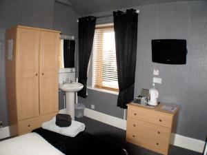 um quarto com uma cama, um lavatório e um lavatório. em Vaila Guest House em Aberdeen