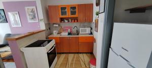 a small kitchen with wooden cabinets and a refrigerator at Apartman Ograde in Bosanski Novi +1 photo