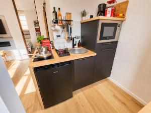 a small kitchen with a sink and a microwave at MRODBNB - Appart Neuf - Aperçu Mer - 25m Plage & Resto - Ciné - cheminée - Popcorn in Cancale