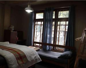 a bedroom with a bed and a window with blue curtains at Ang Ds Homestay in Sonāda