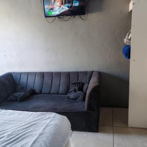 a couch in a room with a tv on a wall at Prime Guest Inn in Benoni