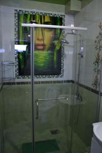 a bathroom with a shower with a painting on the wall at VIP Mini Hotel in Semey
