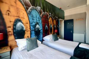 two beds in a room with a wall with a mural at Vikings Accommodation in York