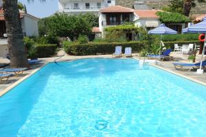 a large blue swimming pool with chairs and umbrellas at Jasmine apartments in Pythagoreio