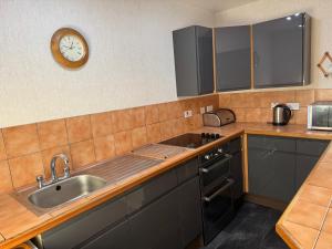 a kitchen with a sink and a clock on the wall at Cove Cottage Ellary in Lochgilphead