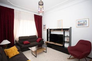 a living room with a couch and a television at Apartamento en Residencia Brooks Iberia in Tangier