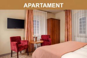 a bedroom with a bed and two chairs and a table at Hotel Miodowy Młyn in Opatów