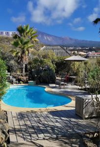a swimming pool with a table and an umbrella at Bella Vista - Finca Tabaiba in Icod de los Vinos