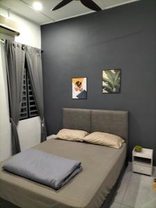 a bed in a bedroom with a gray wall at 910 Entire Homestay Seremban Town, Templer, Lobak, Lekas Highway in Seremban
