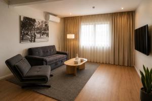 a living room with a couch and a chair and a table at Dizengoff Square Boutique Aparthotel - by BAR COLLECTION in Tel Aviv