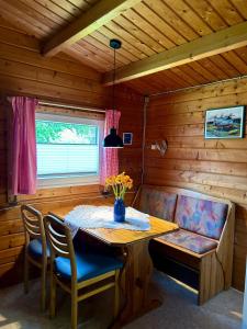 a wooden room with a table and chairs and a bench at Haus Seerobbe-Blockhaus im Garten in Fehmarn