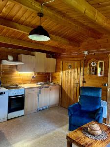 a kitchen with a blue chair and a table at Haus Seerobbe-Blockhaus im Garten in Fehmarn