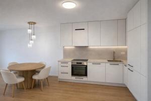 a kitchen with white cabinets and a table and chairs at Villa La Pollo in Senec