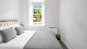 a white bedroom with a white bed and a window at Govandale Seaviews in Kingarth
