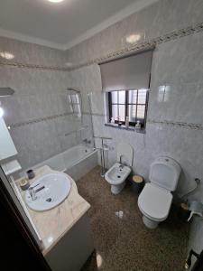 a bathroom with a sink and a toilet and a tub at Constança House in Corroios +17 photos