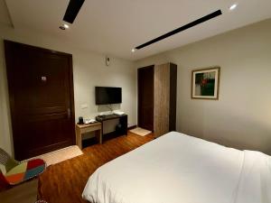 a bedroom with a white bed and a television at Tower 92 - Hotel in Ghora