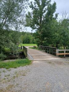 a wooden bridge over a field with trees at Sur l'Oneux in Hotton +3 photos