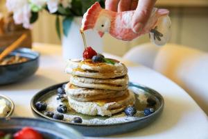 a person pouring syrup onto a stack of pancakes at Be My Guest Champagne in Gueux +61 photos