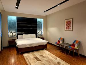 a bedroom with a bed and two chairs and a window at Tower 92 - Hotel in Ghora