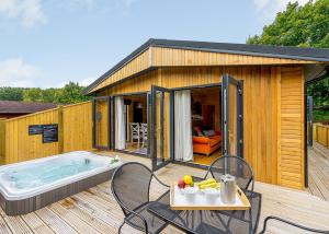 a small house with a hot tub on a deck at Ashlea Pools Lodges in Hoptonheath