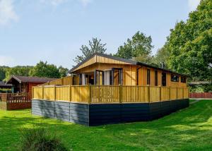 a small house on a lawn with a fence at Ashlea Pools Lodges in Hoptonheath