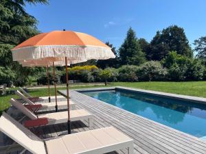 a pool with two chairs and an umbrella at Be My Guest Champagne in Gueux