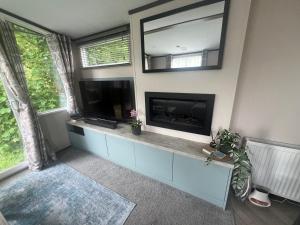 a living room with a fireplace and a flat screen tv at Hardy's Hut in Felton