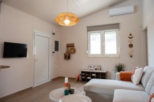 a living room with a white couch and a tv at Lagonisi Olive Retreat in Kalívia Thorikoú