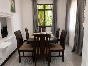 a dining room with a table and chairs and a window at Boma Retreat in Boma la Ngombe